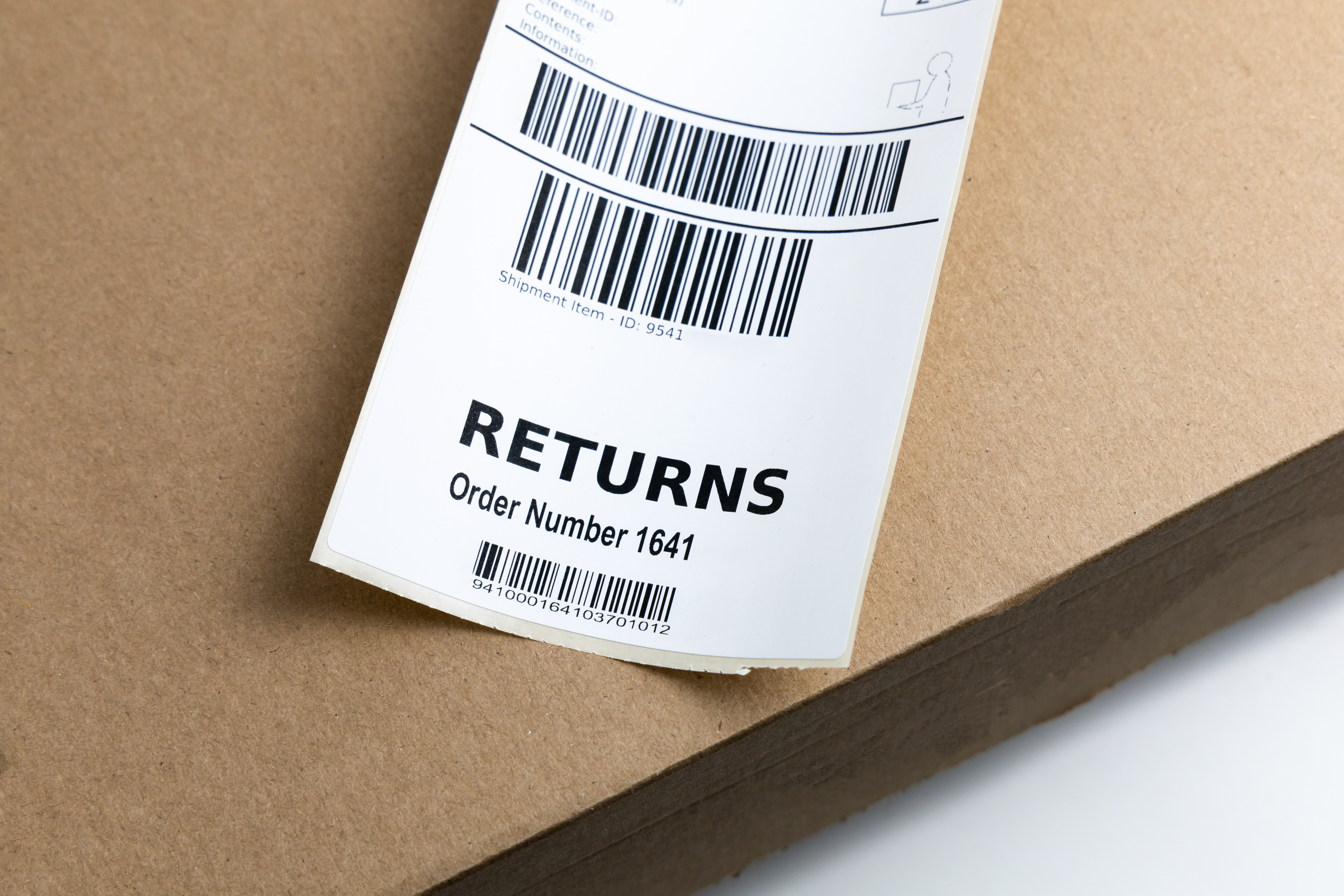 A close-up of a returns shipping label with barcodes and the text RETURNS Order Number 1641 placed on top of a brown cardboard box.