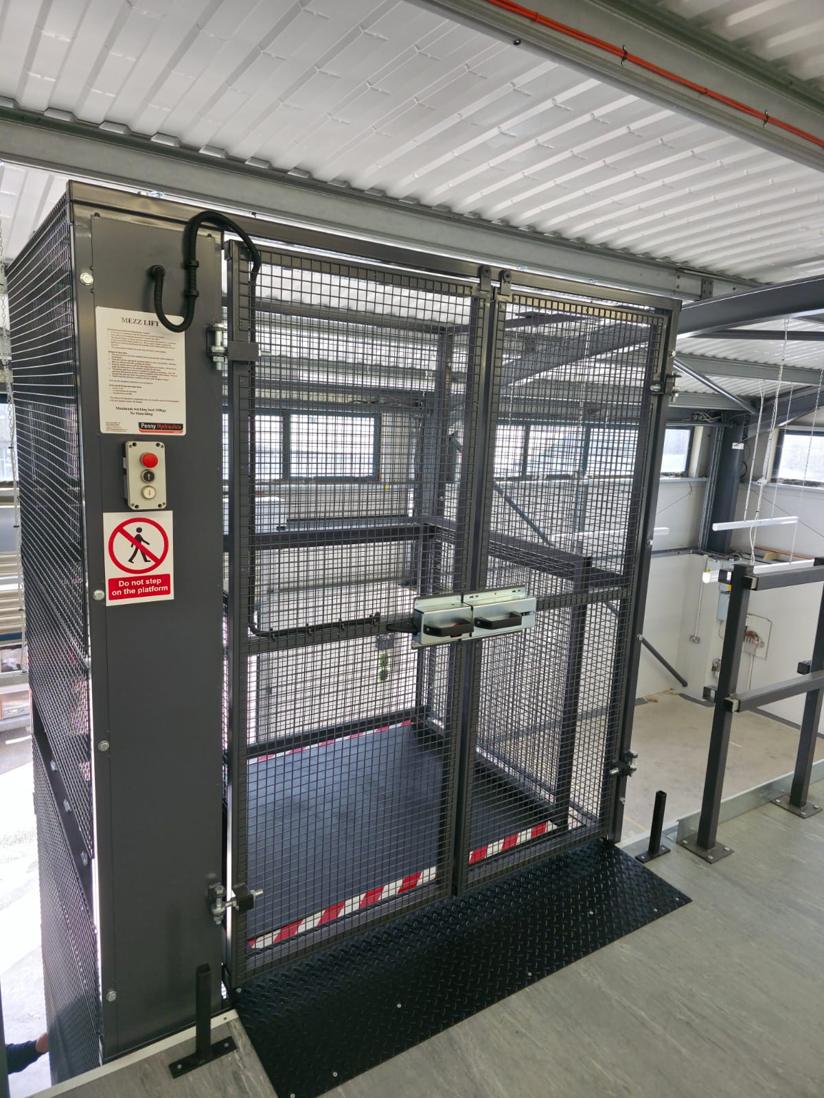 A distorted, green-tinted image with horizontal lines obscuring an outdoor scene that includes a metal fence and several vertical structures or poles.